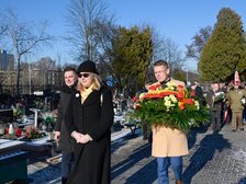 Alejka na cmentarzu. Kondukt ludzi niosących wiązanki. Na pierwszym planie wiceprezydent Łodzi Adam Wieczorek niosący wieniec z wstęgą na napisem Prezydent Miasta Łodzi. Obok niego idzie Przewodniczący Rady Miejskiej w Łodzi Marcin Gołaszewski.