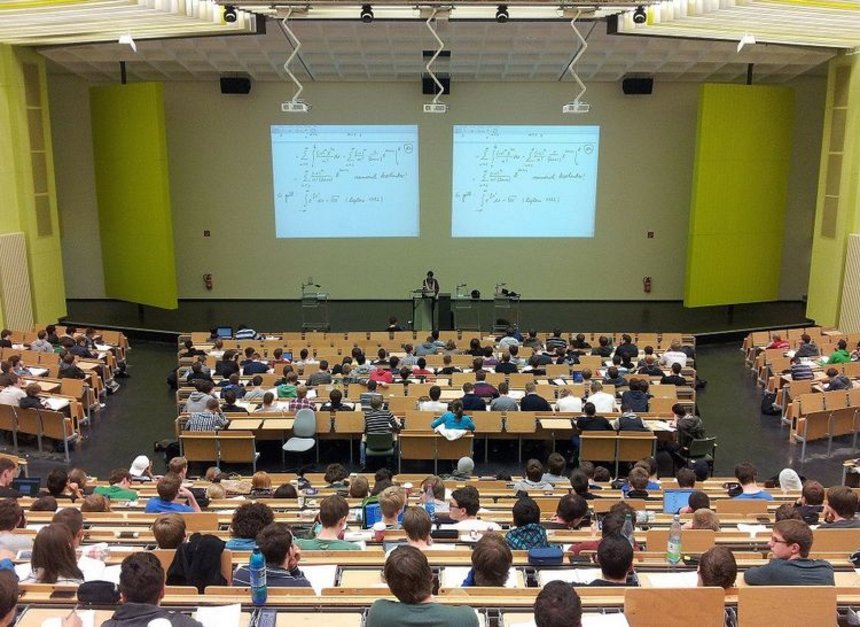 - sala wykładowa - aula wypełniona studentami siedzącymi przy długich stołach, w centrum katedra z wykładowcą i wyświetlona na dwóch ekranach ściennych prezentacja sala wykładowa - aula wypełniona studentami siedzącymi przy długich stołach, w centrum katedra z wykładowcą i wyświetlona na dwóch ekranach ściennych prezentacja