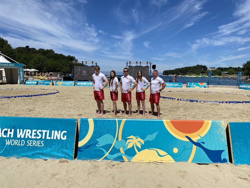 na zdjęciu zawodnicy Master Łódź na arenie do beach wrestlingu wraz z trenerami ubrani w narodowe barwy