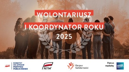 Zdjęcie w kolorach beżowo brązowych z białym napisem na czerwonym tle w centralnym punkcie zdjęcia. "WOLONTARIUSZ I KOORDYNATOR ROKU 2025. W tle grupa ludzi stojąca w kręgu i obejmująca się. W oddali widać drzewa rozpływające się we mgle.